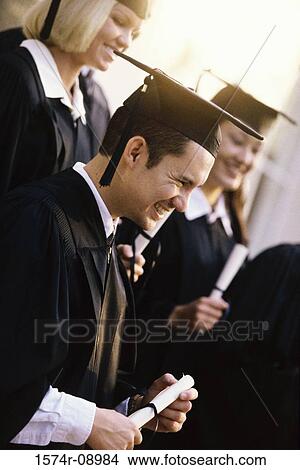 Picture - Side profile of young graduates holding diplomas smiling. Fotosearch