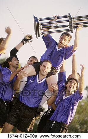 Stock Image - Soccer players cheering with their winning trophy. Fotosearch