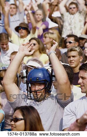 Stock Image - Spectator wearing a football helmet and cheering. Fotosearch