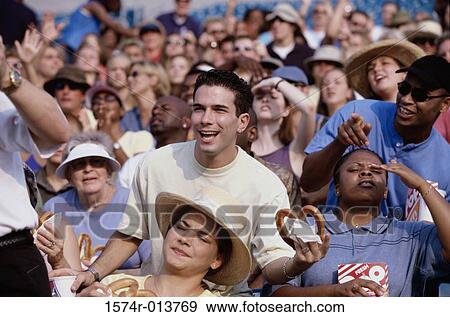 Stock Photo - Spectators in a stadium eating pretzels. Fotosearch