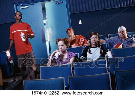 Stock Image - Teenage boy searching for his seat in a movie theater. Fotosearch