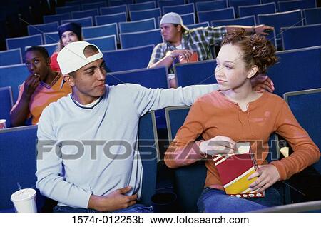 Stock Image - Teenage boy with a teenage girl sitting in a movie theater. Fotosearch