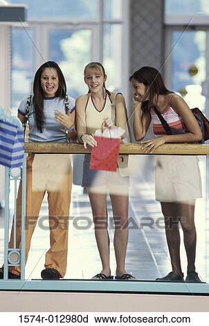 Stock Image - Three teenage girls leaning over a railing. Fotosearch