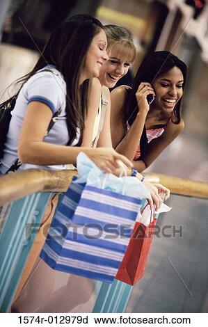 Stock Image - Three teenage girls standing with shopping bags. Fotosearch