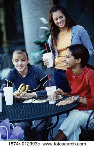 Three young women eating at a cafe View Large Photo Image Stock Image - Three young women eating at a cafe. Fotosearch