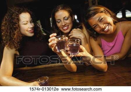 Three young women toasting with glasses in a bar View Large Photo Image Stock Image - Three young women toasting with glasses in a bar. Fotosearch
