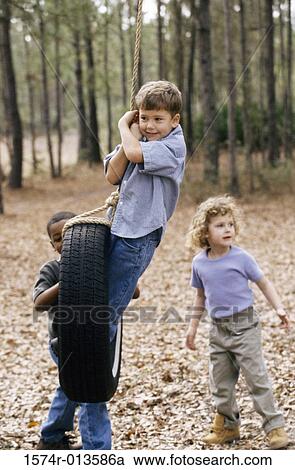 Two boys and a girl playing on a tire swing View Large Photo Image Stock Image - Two boys and a girl playing on a tire swing. Fotosearch