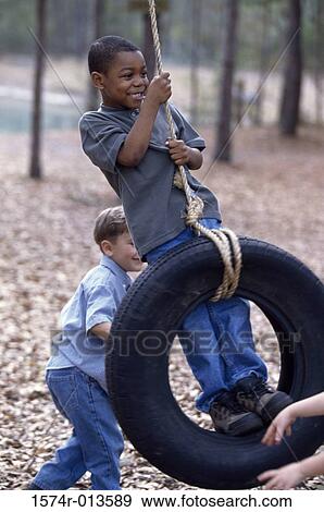 Two boys playing on a tire swing View Large Photo Image Stock Photo - Two boys playing on a tire swing. Fotosearch