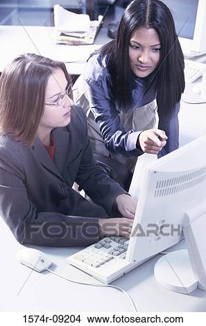 Picture - Two businesswomen working on a computer. Fotosearch