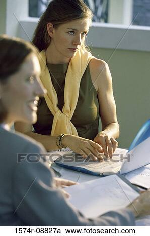 Stock Image - Two businesswomen working on a laptop. Fotosearch