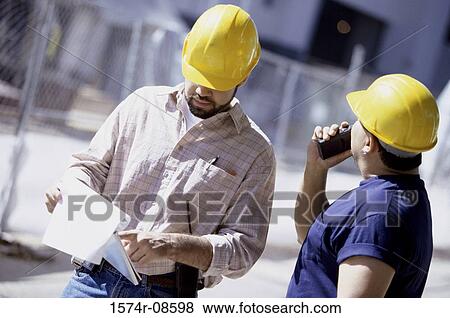 Two foremen standing at a construction site View Large Photo Image Stock Photo - Two foremen standing at a construction site. Fotosearch