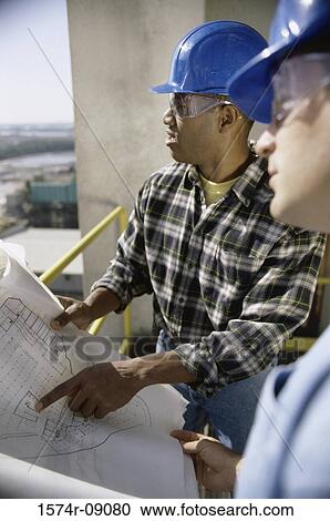 Stock Image - Two foremen working on blueprints. Fotosearch