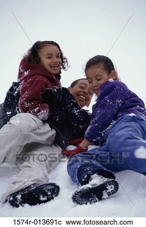 Stock Image - Two girls and a boy playing in snow. Fotosearch