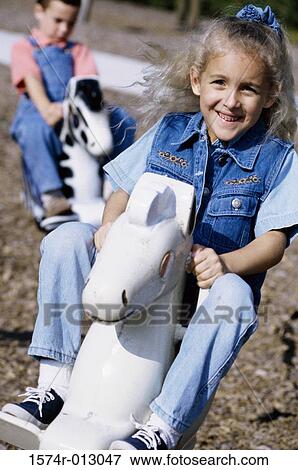 Stock Photo - Two girls sitting on rocking horses. Fotosearch