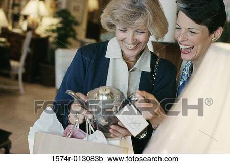 Two mature women holding an antique teapot in a store View Large Photo Image Stock Image - Two mature women holding an antique teapot in a store. Fotosearch