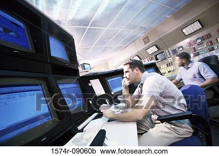 Two mid adult men sitting in a electric power control room View Large Photo Image Stock Image - Two mid adult men sitting in a electric power control room. Fotosearch