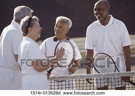 Stock Image - Two senior couples on a tennis court. Fotosearch