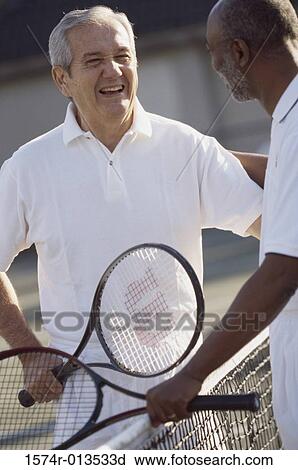 Stock Image - Two senior men standing on a tennis court. Fotosearch