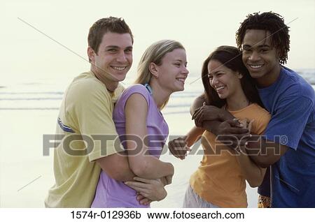 Stock Image - Two teenage couples embracing on the beach. Fotosearch