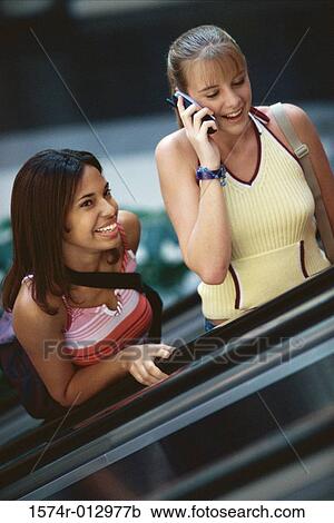Two teenage girls standing on an escalator View Large Photo Image Stock Image - Two teenage girls standing on an escalator. Fotosearch