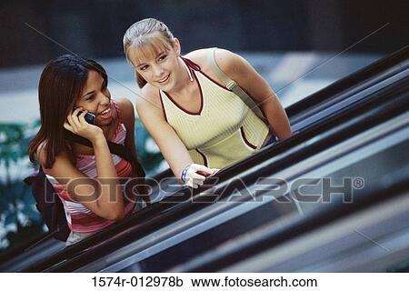 Two teenage girls standing on an escalator View Large Photo Image Stock Image - Two teenage girls standing on an escalator. Fotosearch