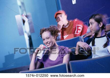 Stock Image - Two teenage girls watching a movie in a theater. Fotosearch