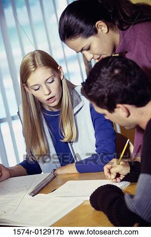 Stock Image - Two teenage girls with a teenage boy studying. Fotosearch
