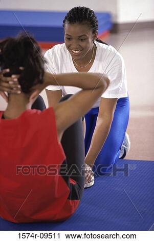 Stock Image - Two women exercising on the floor. Fotosearch