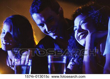 Two young women and a young man in a bar View Large Photo Image Stock Image - Two young women and a young man in a bar. Fotosearch