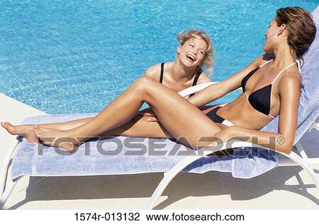 Two young women laughing at the poolside View Large Photo Image Stock Image - Two young women laughing at the poolside. Fotosearch