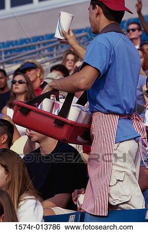 Vendor showing drinks to spectators in a stadium View Large Photo Image Stock Photograph - Vendor showing drinks to spectators in a stadium. Fotosearch