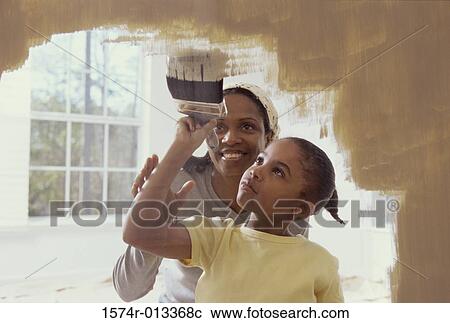 Woman and her daughter painting a wall View Large Photo Image Stock Image - Woman and her daughter painting a wall. Fotosearch