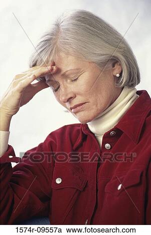 Stock Image - Woman holding her forehead in pain. Fotosearch