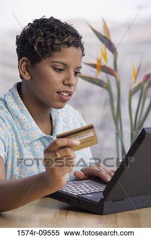 Woman operating a laptop holding a credit card View Large Photo Image Stock Photography - Woman operating a laptop holding a credit card. Fotosearch