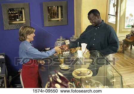 Woman standing behind a counter serving a man sweets View Large Photo Image Stock Image - Woman standing behind a counter serving a man sweets. Fotosearch