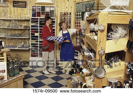 Woman standing in a store with a female store clerk View Large Photo Image Stock Image - Woman standing in a store with a female store clerk. Fotosearch