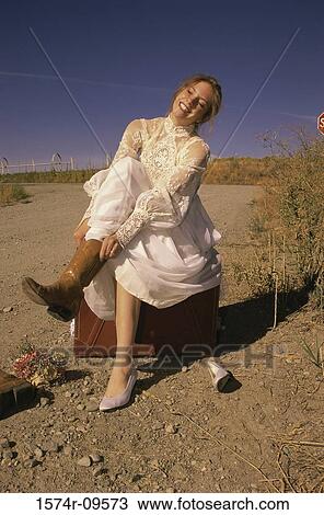 Young bride sitting on a suitcase outdoors putting on boots View Large Photo Image Stock Image - Young bride sitting on a suitcase outdoors putting on boots. Fotosearch