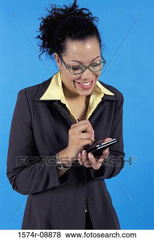 Young businesswoman operating a hand held device View Large Photo Image Stock Photo - Young businesswoman operating a hand held device. Fotosearch