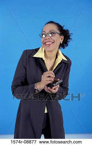 Stock Photo - Young businesswoman smiling holding a hand held device. Fotosearch