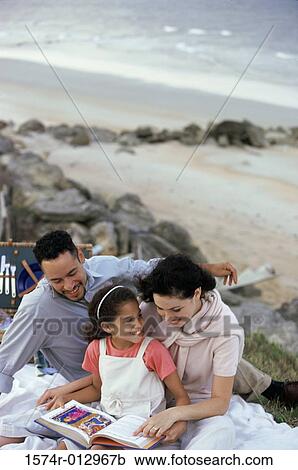 Young couple and their daughter reading a book on the beach View Large Photo Image Stock Image - Young couple and their daughter reading a book on the beach. Fotosearch
