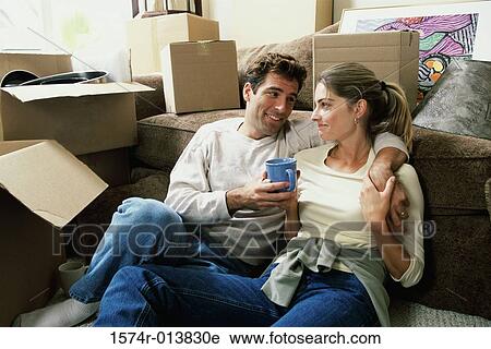 Stock Image - Young couple holding a cup of coffee looking at each other. Fotosearch