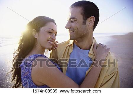 Young couple holding each other at the beach View Large Photo Image Stock Photo - Young couple holding each other at the beach. Fotosearch