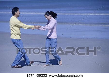 Stock Image - Young couple playing on the beach. Fotosearch