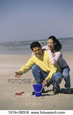 Young couple playing on the beach View Large Photo Image Stock Photograph - Young couple playing on the beach. Fotosearch