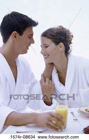 Young couple sitting together at a table smiling View Large Photo Image Picture - Young couple sitting together at a table smiling. Fotosearch