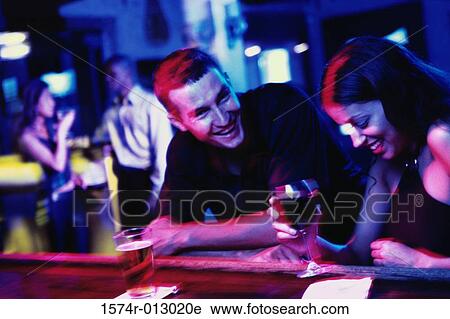Young couple standing at a bar counter View Large Photo Image Stock Image - Young couple standing at a bar counter. Fotosearch