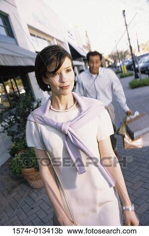 Young couple walking on a sidewalk in a market View Large Photo Image Stock Image - Young couple walking on a sidewalk in a market. Fotosearch