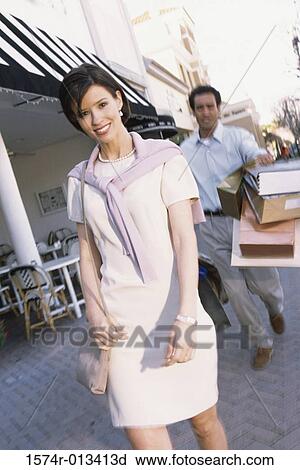 Stock Image - Young couple walking on a sidewalk in a market. Fotosearch