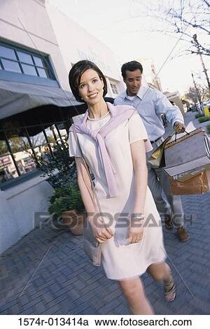 Young couple walking on a sidewalk in a market View Large Photo Image Stock Image - Young couple walking on a sidewalk in a market. Fotosearch