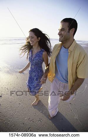 Young couple walking together at the beach View Large Photo Image Stock Image - Young couple walking together at the beach. Fotosearch